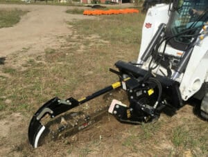 Used skid steer trencher attachment in use.