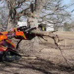 skid steer grapple picking up logs