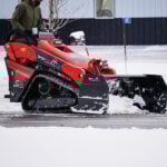 mini skid snow pusher picking up snow