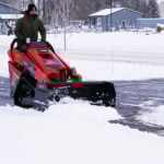 mini skid steer snow pusher pushing snow