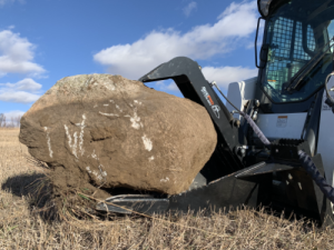stump bucket holding a rock