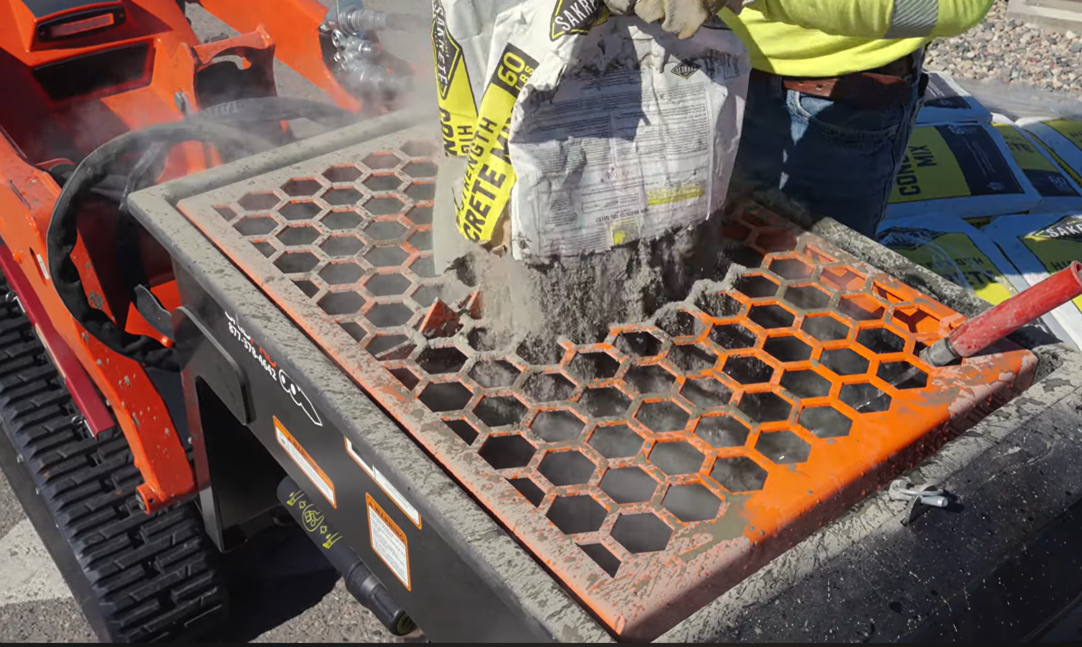 Operator busting a bag of concrete mix on the safety grate